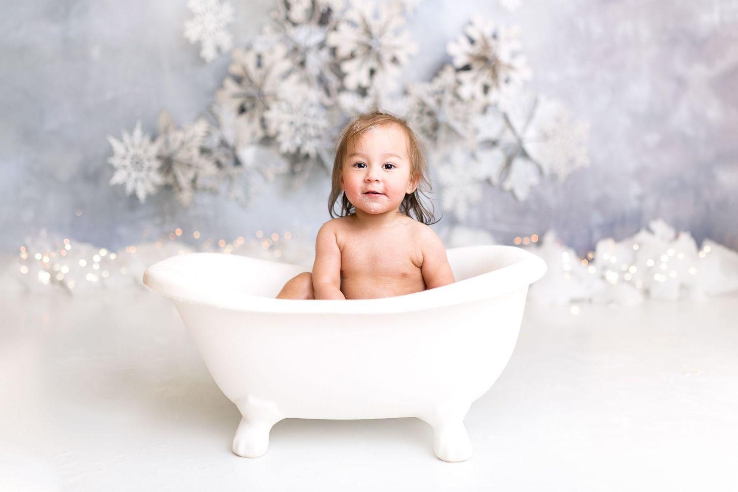 Baby bath photography setup with white snowflake winter backdrop.
