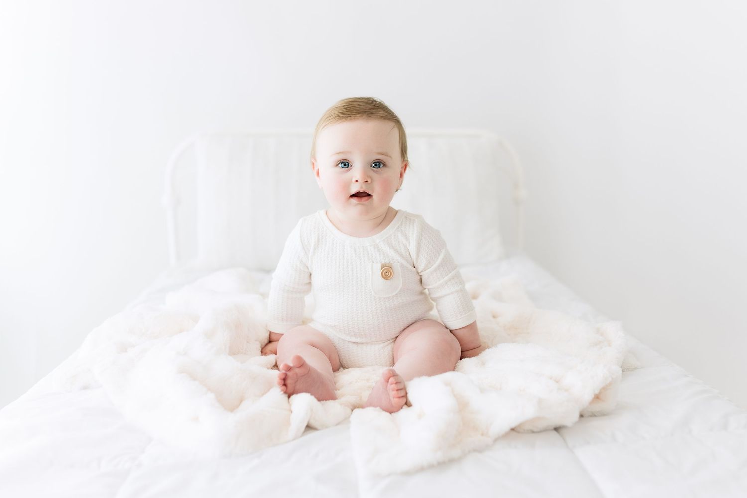 All-white studio portrait with soft textures and minimal styling.