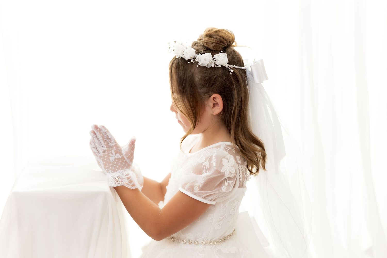 A person meditates in white clothing near a sunny window, creating a peaceful and serene atmosphere.