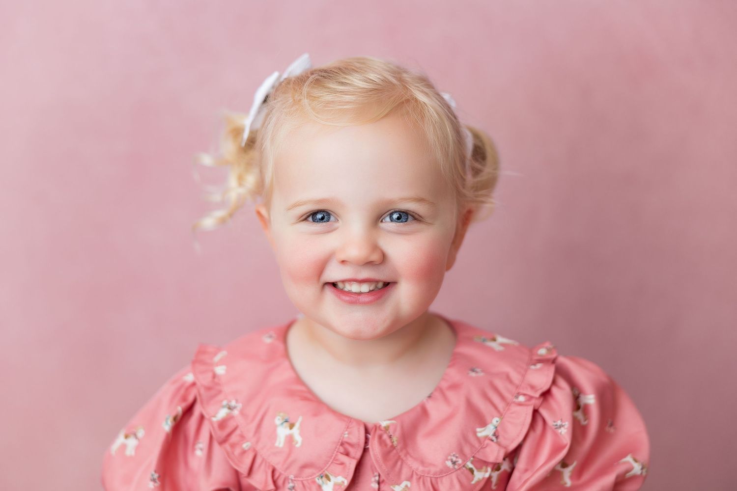 A sweet baby in a pink floral dress smiles and poses against a soft pink background in multiple photos.