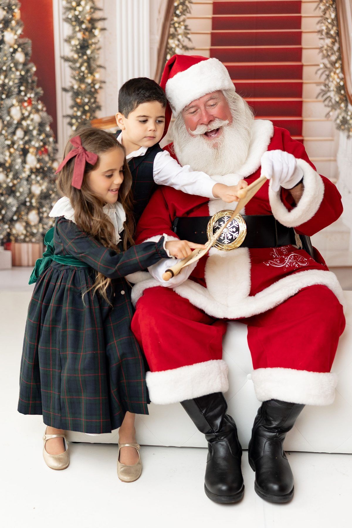 Brother and sister reading their Christmas list with Santa at a Santa mini session