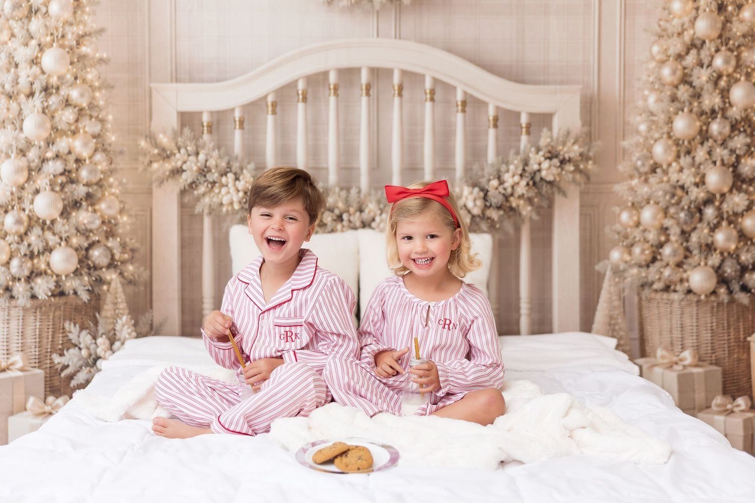 Brother and sister in striped Christmas jammies eating cookies on a white Christmas bed set, Milk and Cookies mini session in Pacific Grove