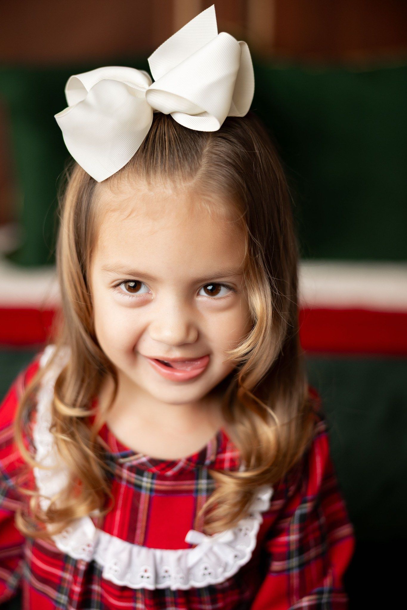 Girl in a red plaid dress and big white bow at a Milk & Cookies Christmas mini session in Pacific Grove