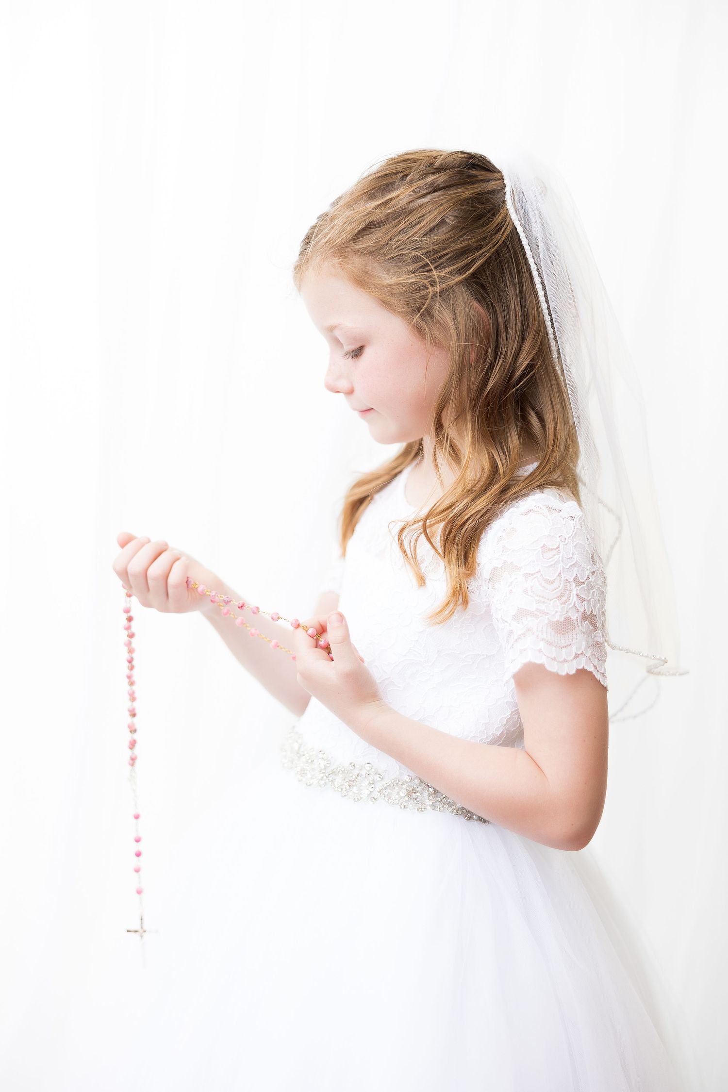 A white high-key photo series of a young girl in a white dress against a light background.