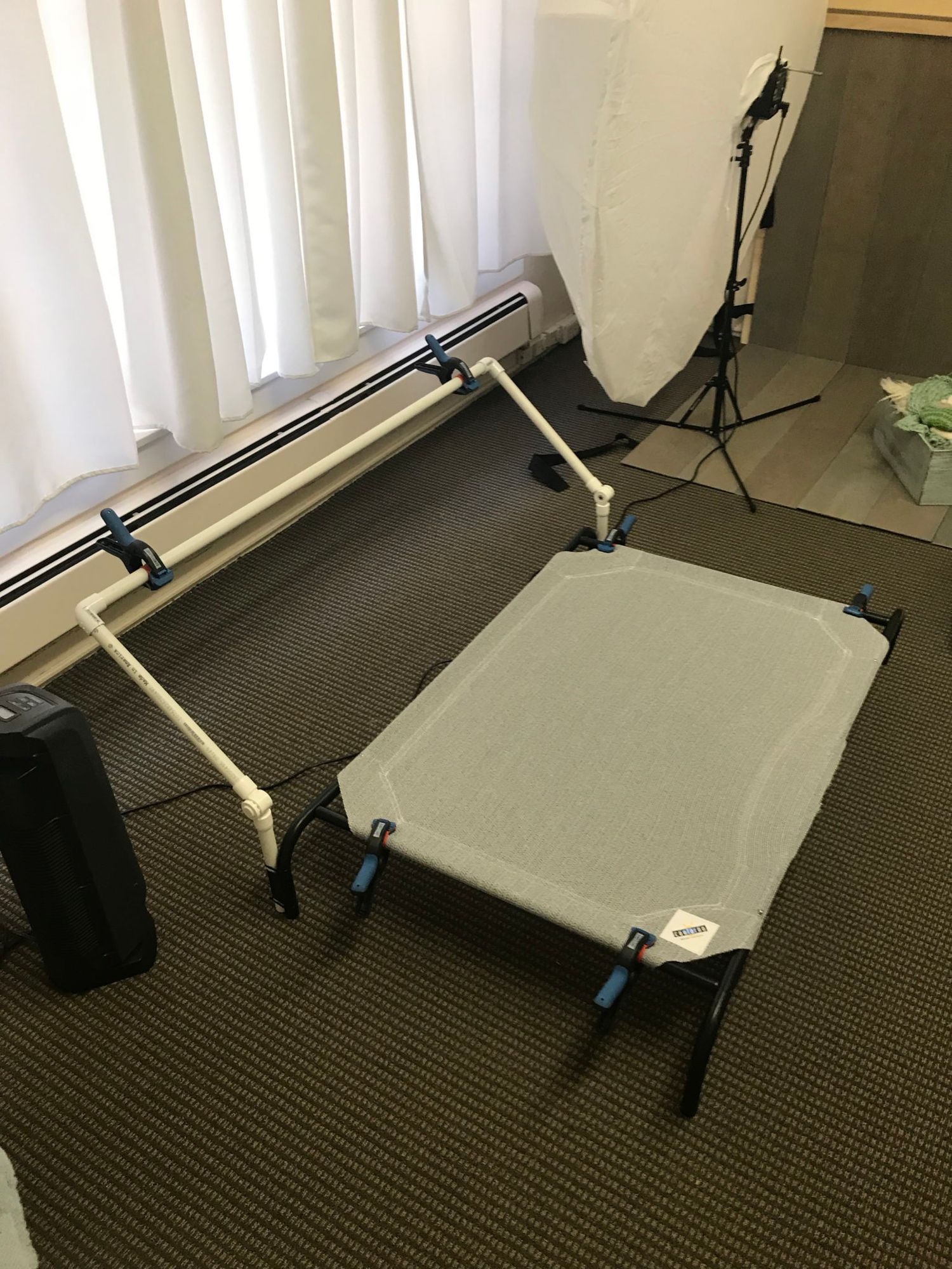 A sequence of photos showing a large white backdrop being set up with lighting equipment and stands in a carpeted room.