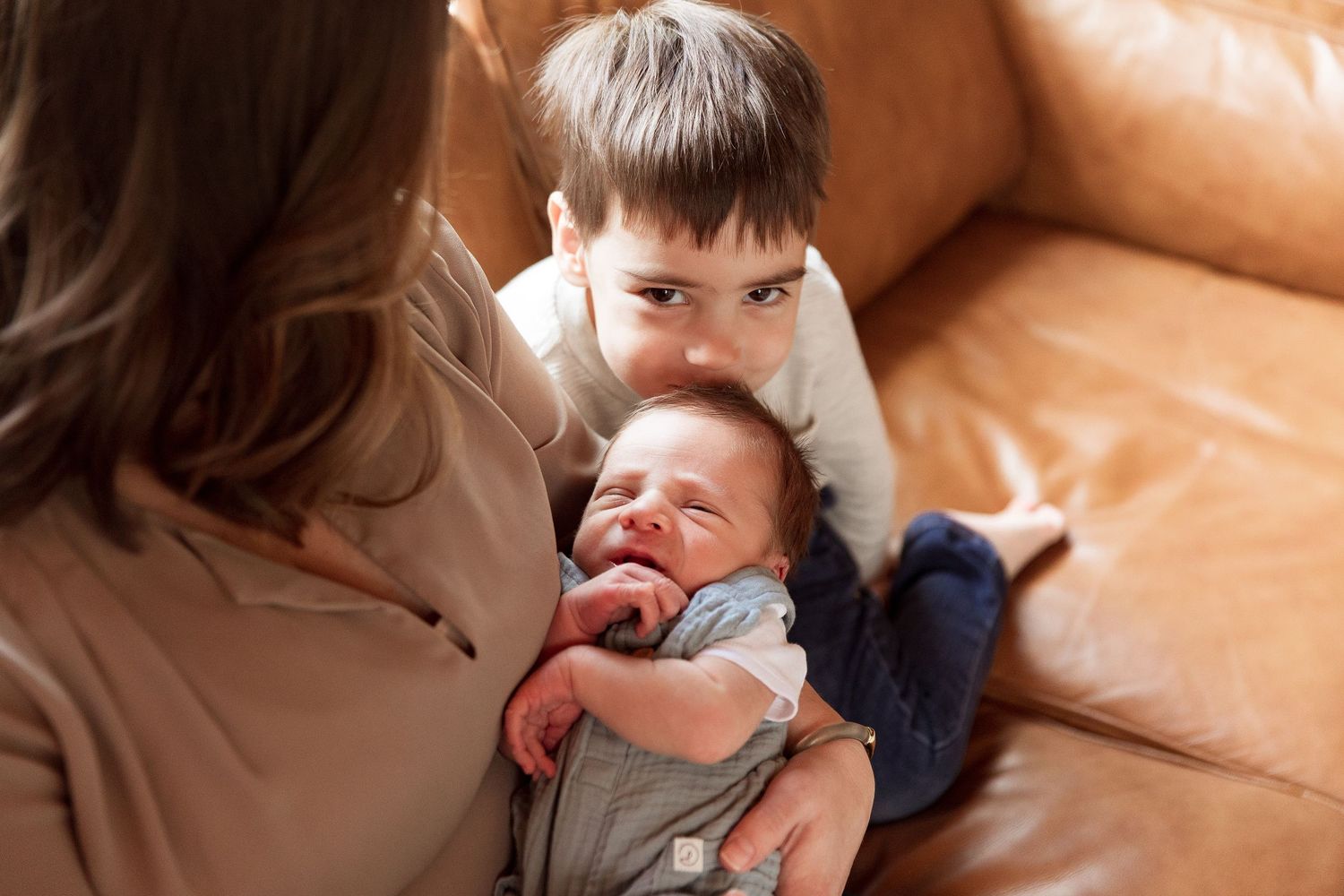 Family bonding moments captured on brown leather couch.