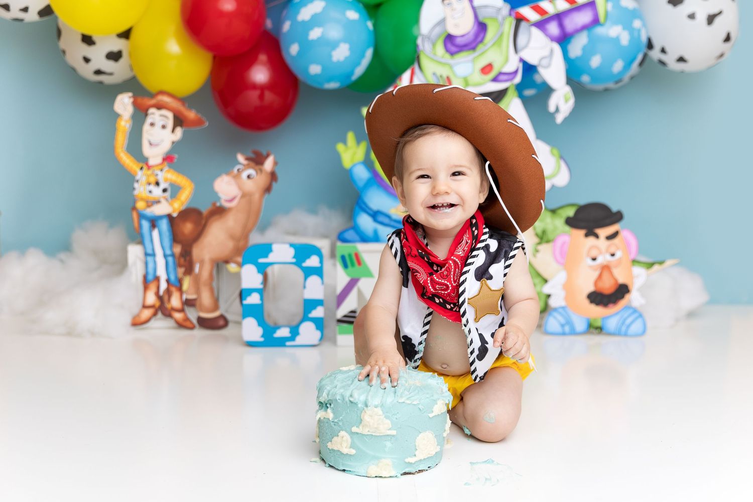 Toy Story cake smash photography setup with character cutouts and festive balloons.
