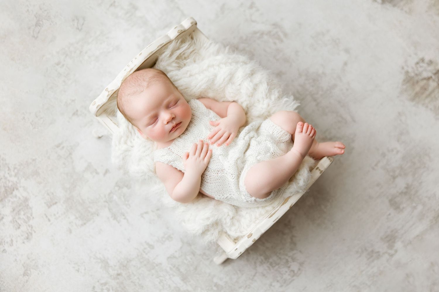 A series of artistic newborn baby portraits showing tiny feet and hands against a white textured backdrop.