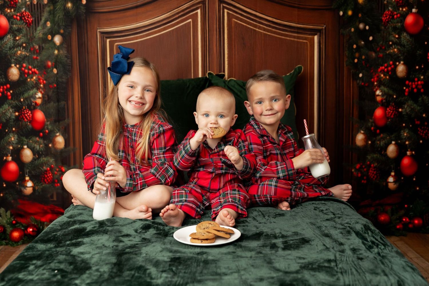 Three siblings in red plaid Christmas jammies enjoying milk and cookies at a holiday mini session in Pacific Grove