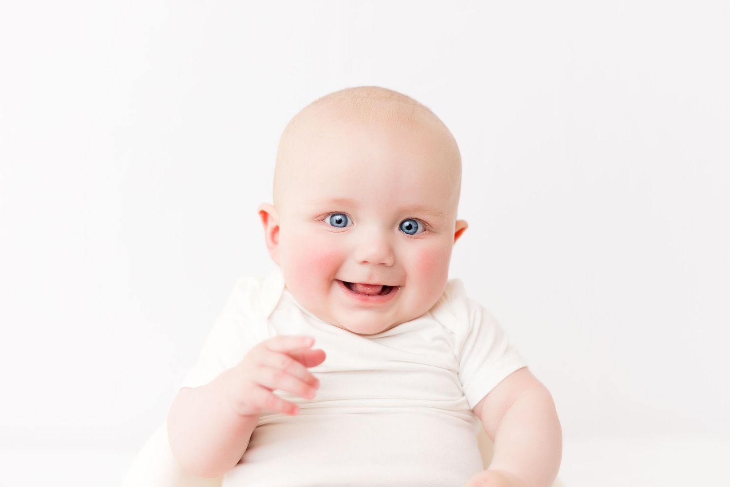 Clean white studio baby photography session with simple styling.