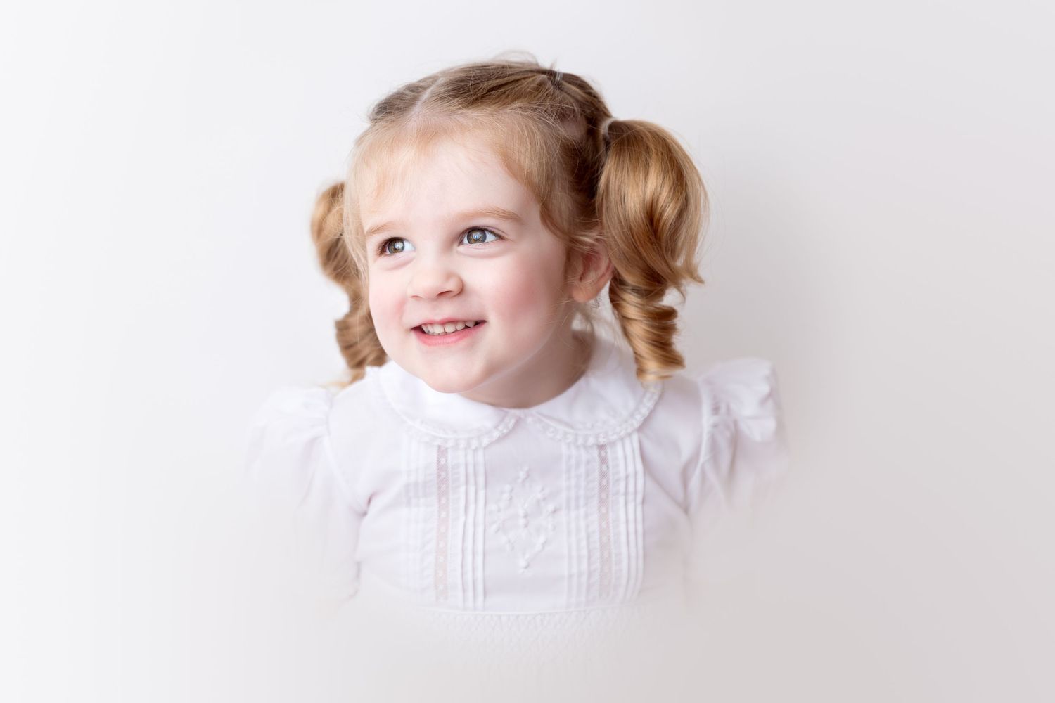 Child portrait series in white dress against light background.
