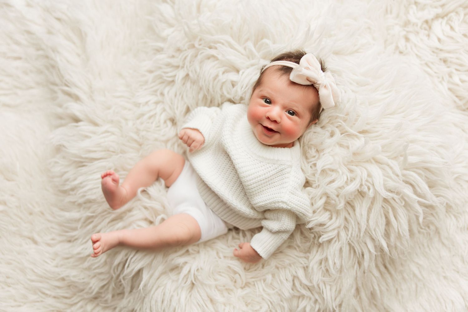 A baby wearing white clothing lies on a soft fluffy white fur blanket in a series of connected photos.