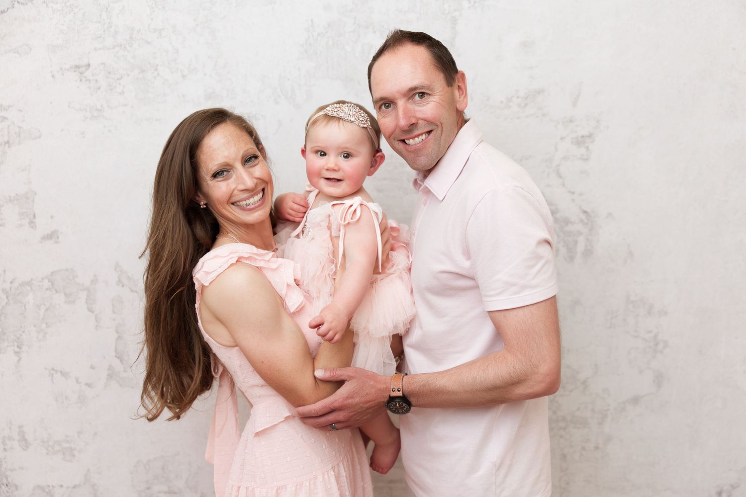 Coordinated family portrait session featuring soft pink and white color palette.