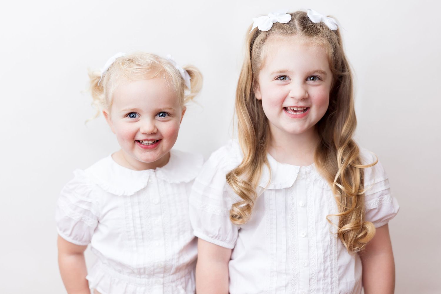 Series of bright studio portraits showing children in white dresses against a light backdrop. Heirloom portrait