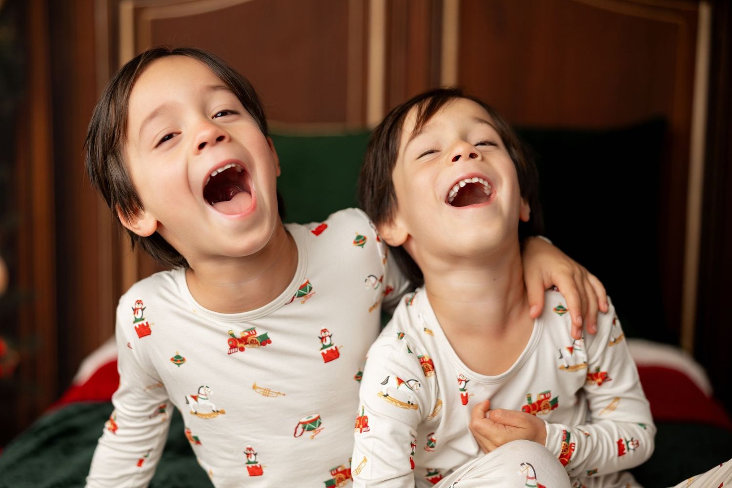 Two children laughing in matching holiday jammies at a Milk & Cookies Christmas mini session in Pacific Grove