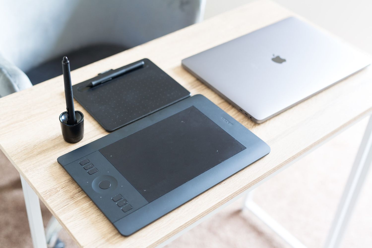 A modern minimalist workspace setup with a graphics tablet, keyboard, and white desk surface.