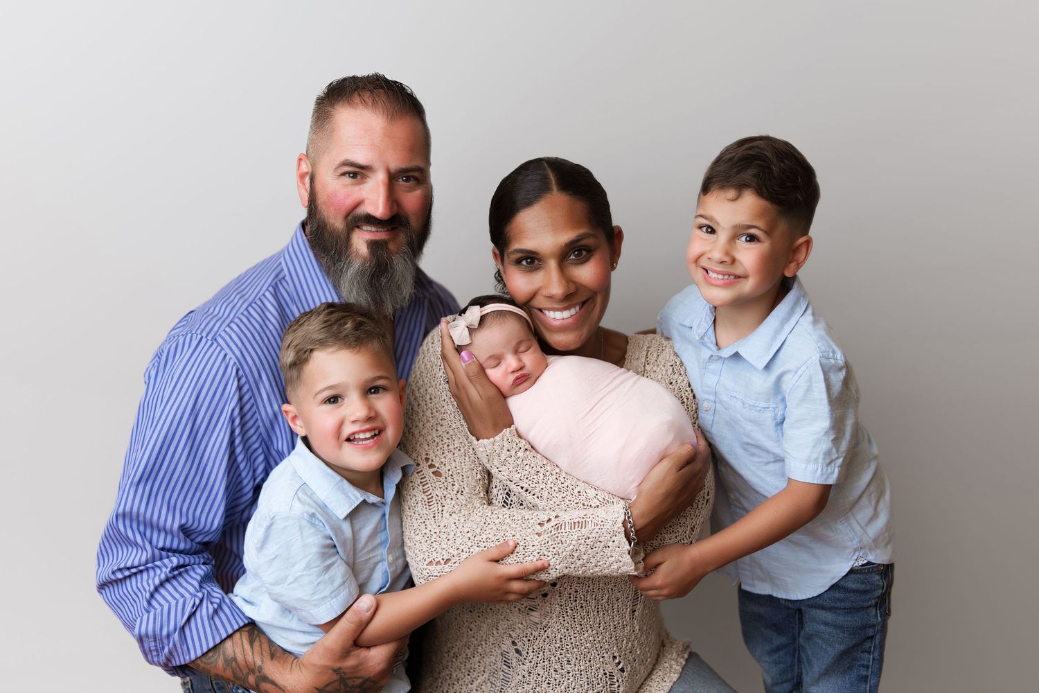 Studio family portrait showing parents and children with newborn baby.