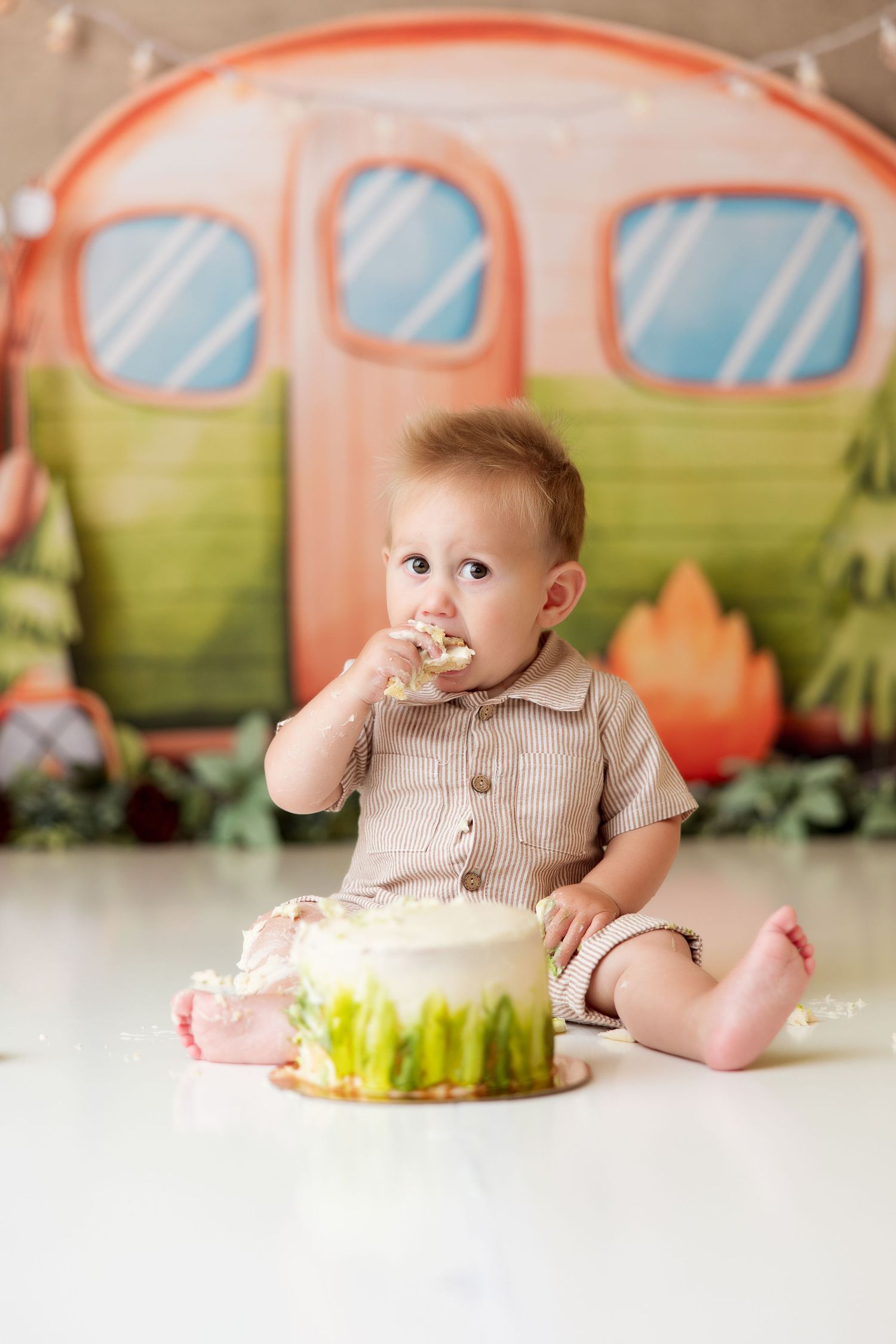 Festive cake smash setup with pink camper backdrop and decorative string lights.