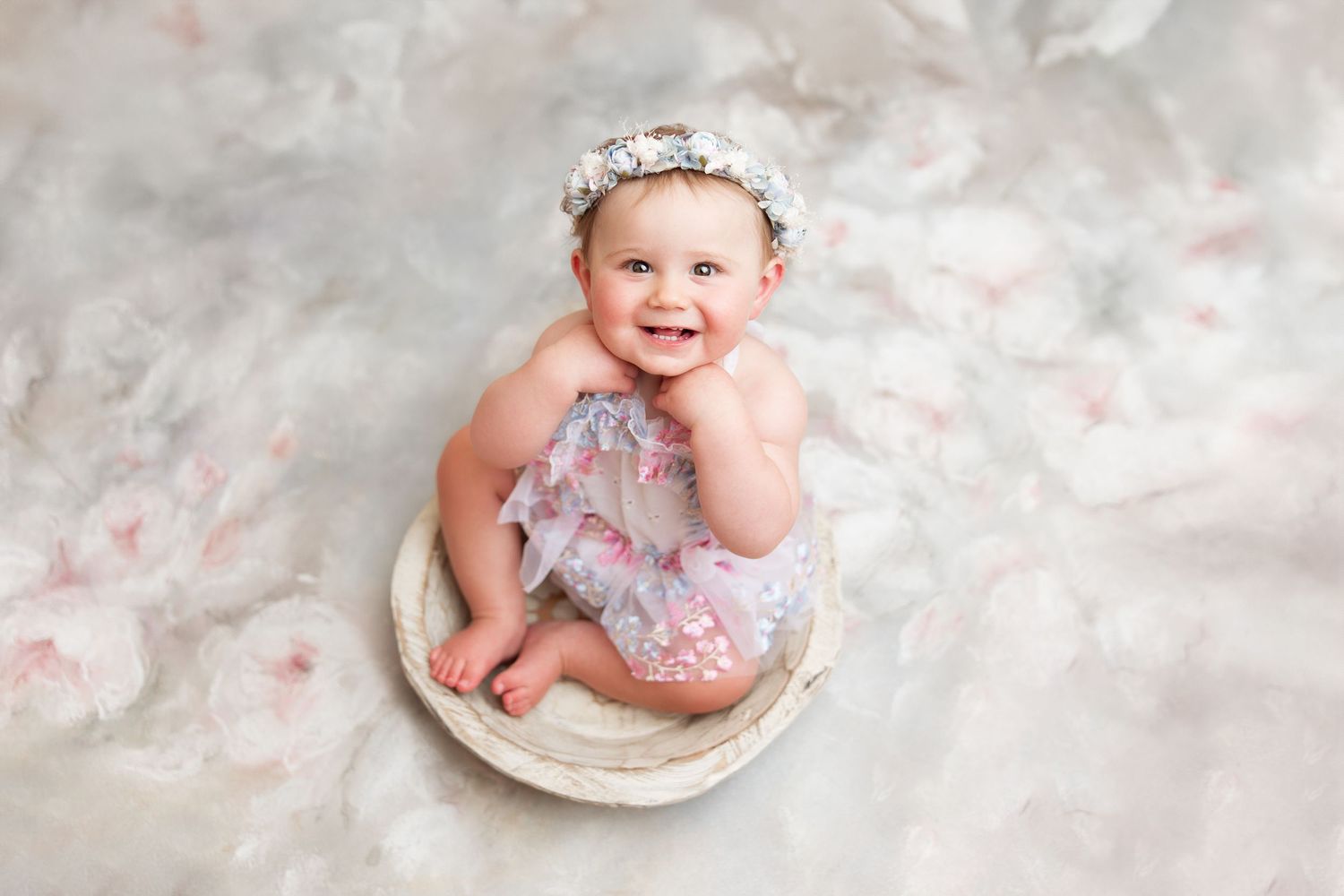 Baby in vintage photo shoot with pink floral decorations and lace dress.