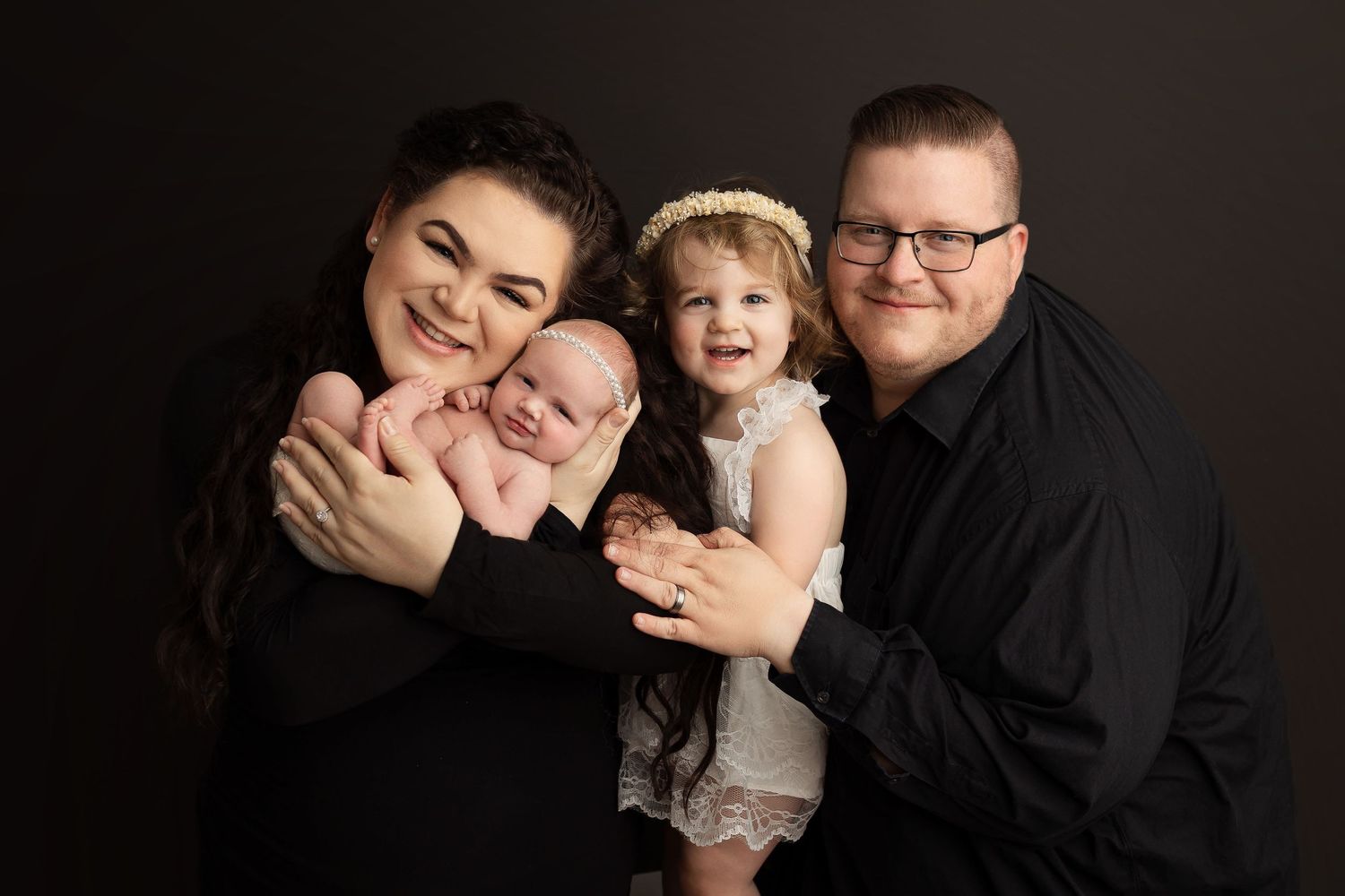 Studio family portrait session showing playful moments against black backdrop.