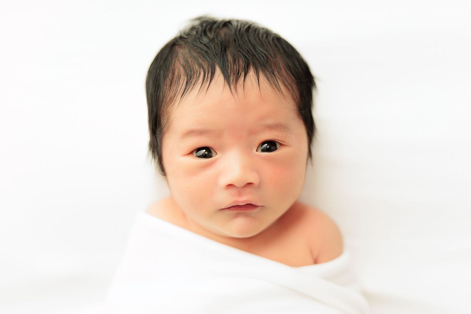 Natural newborn portrait against white background showing peaceful expression.