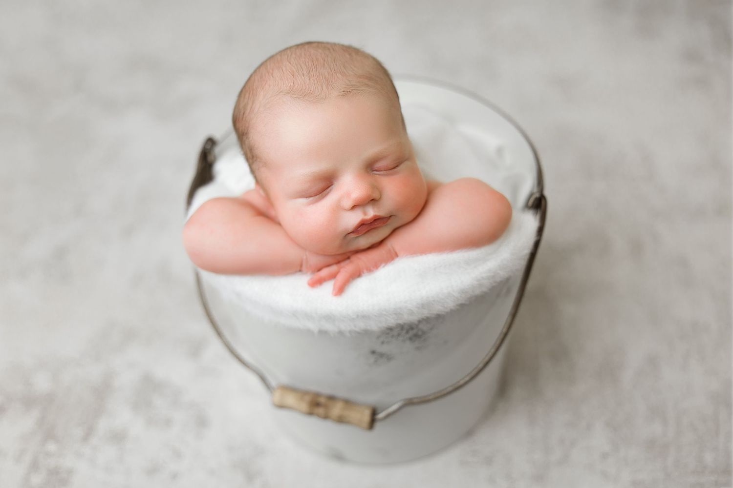 A series of newborn baby photography portraits showing a sleeping infant posed in white bowls against a light backdrop.