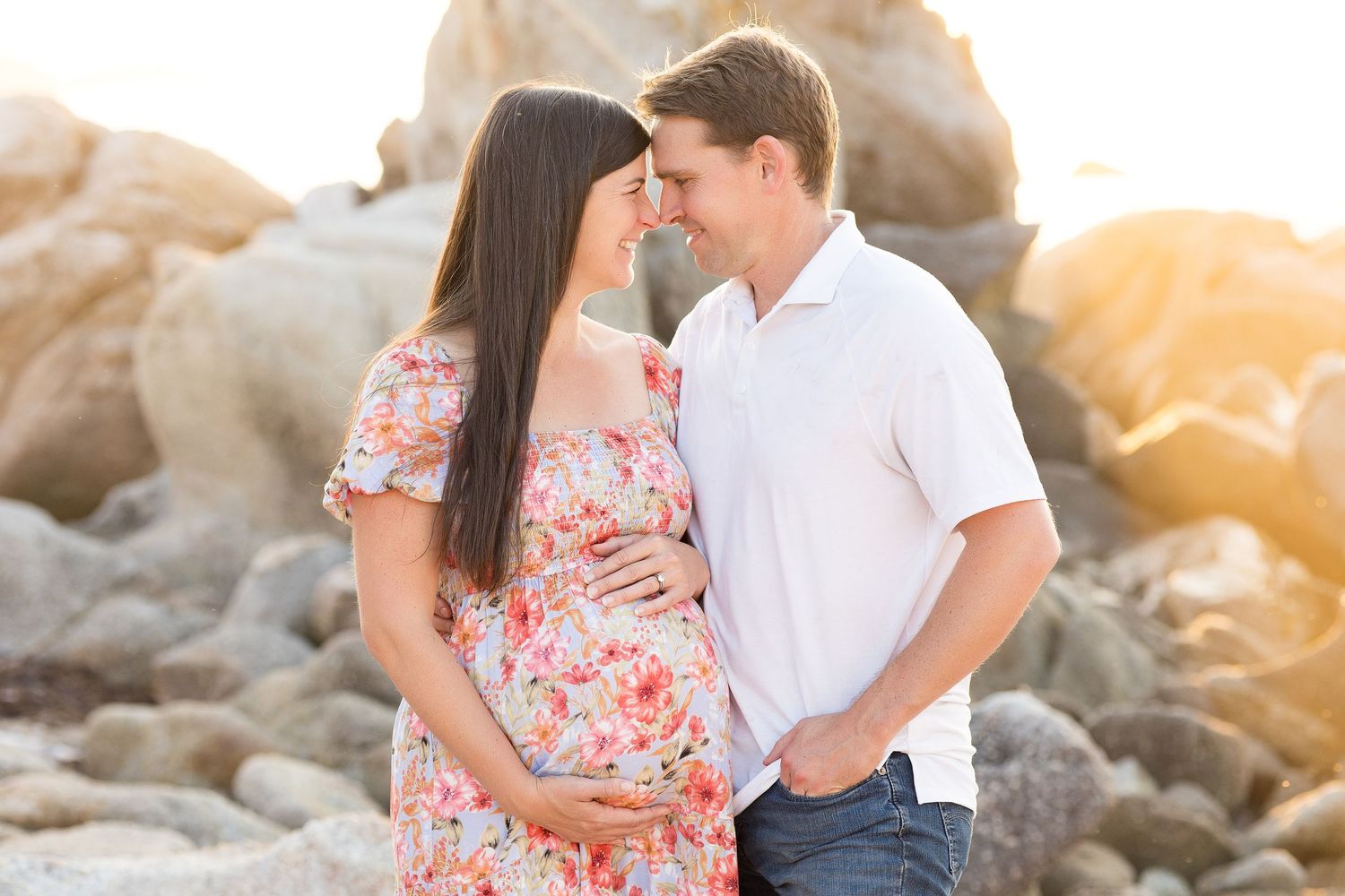 Romantic maternity photo session on a rocky beach during sunset.
