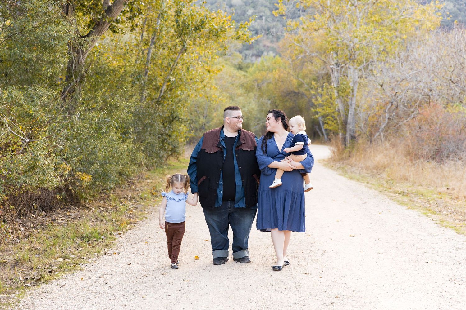 Family walks together on autumn trail surrounded by yellow trees, at Garland Ranch in Carmel Valley.