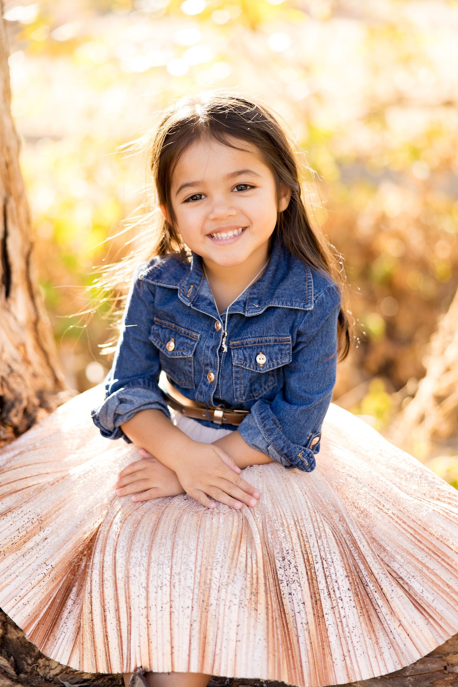 A photo series showing a child in a denim jacket and pink pleated skirt enjoying a sun-drenched outdoor photoshoot.