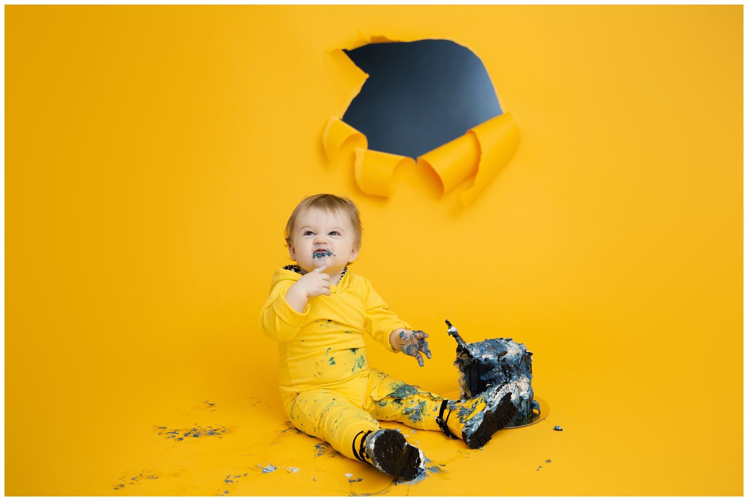 A graduate wearing black cap and gown appears to be falling backwards against a bright yellow background.