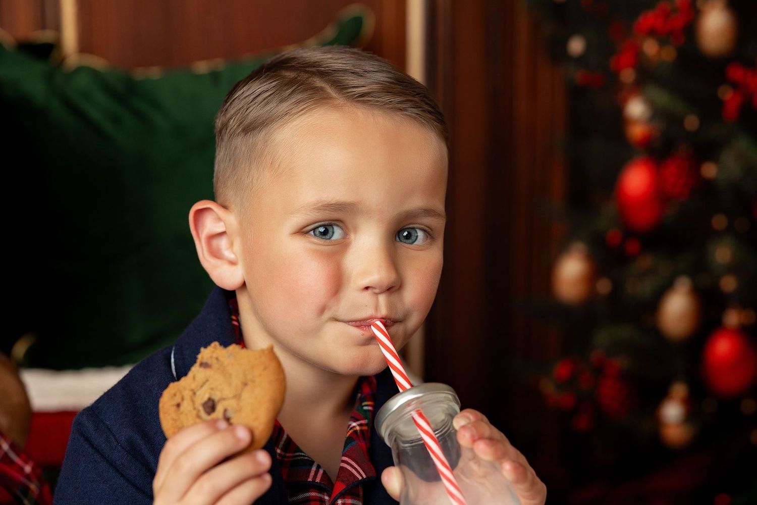 Boy holding a chocolate chip cookie and drinking milk at a Christmas mini session near Carmel