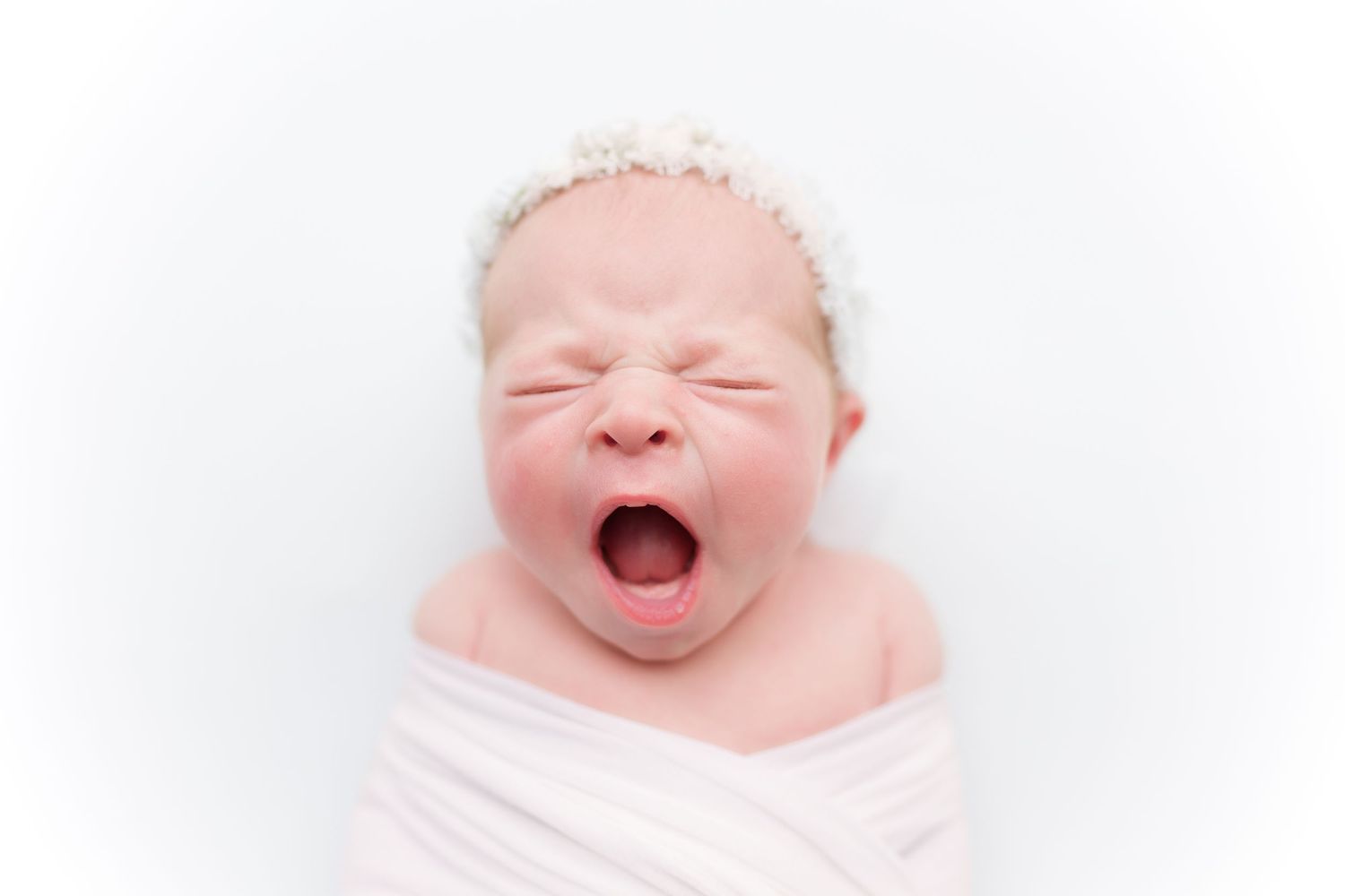Sweet baby smiling and yawning against pure white backdrop.