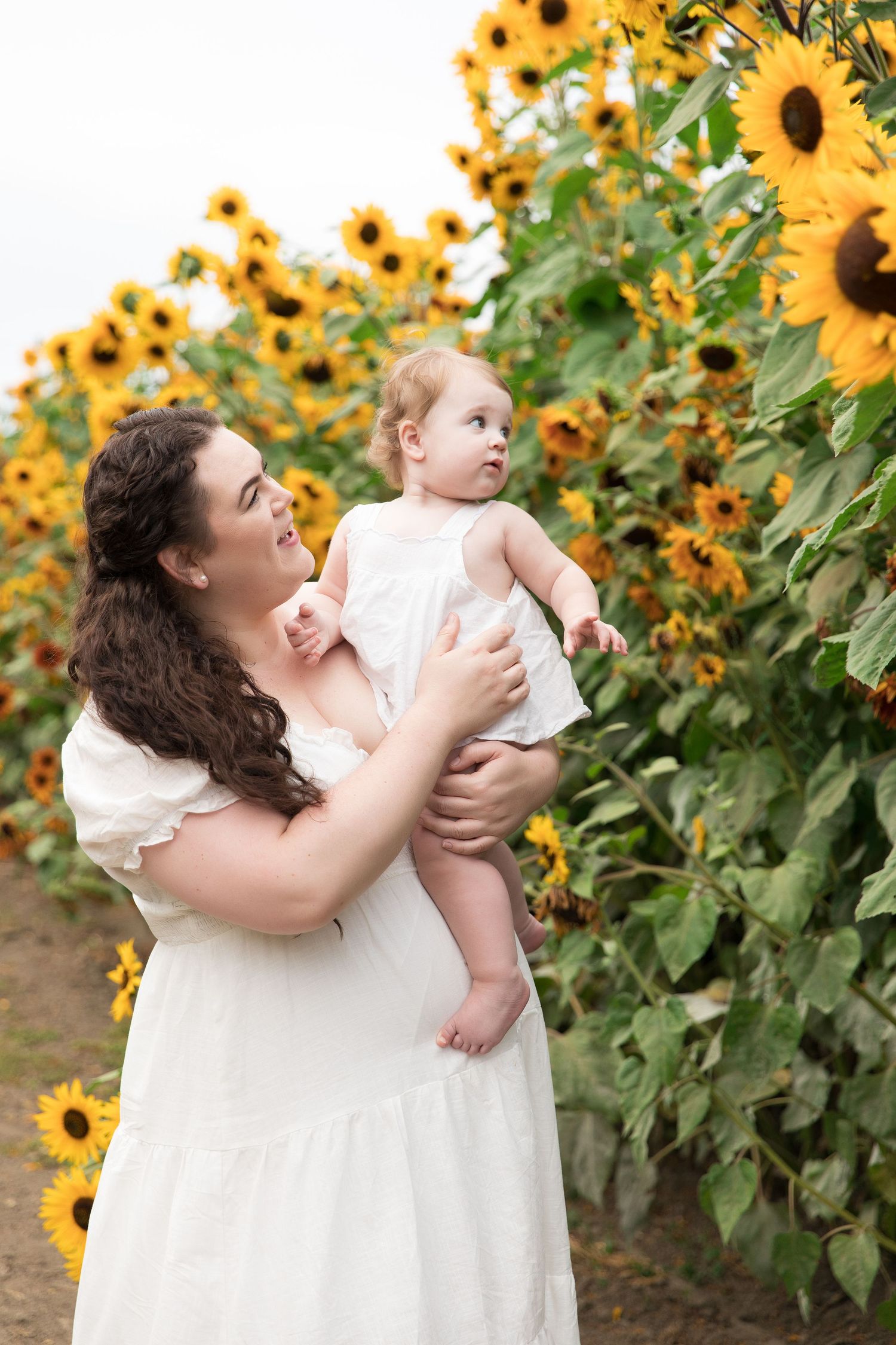 A sweet portrait in a sunflower field with white summer dresses.