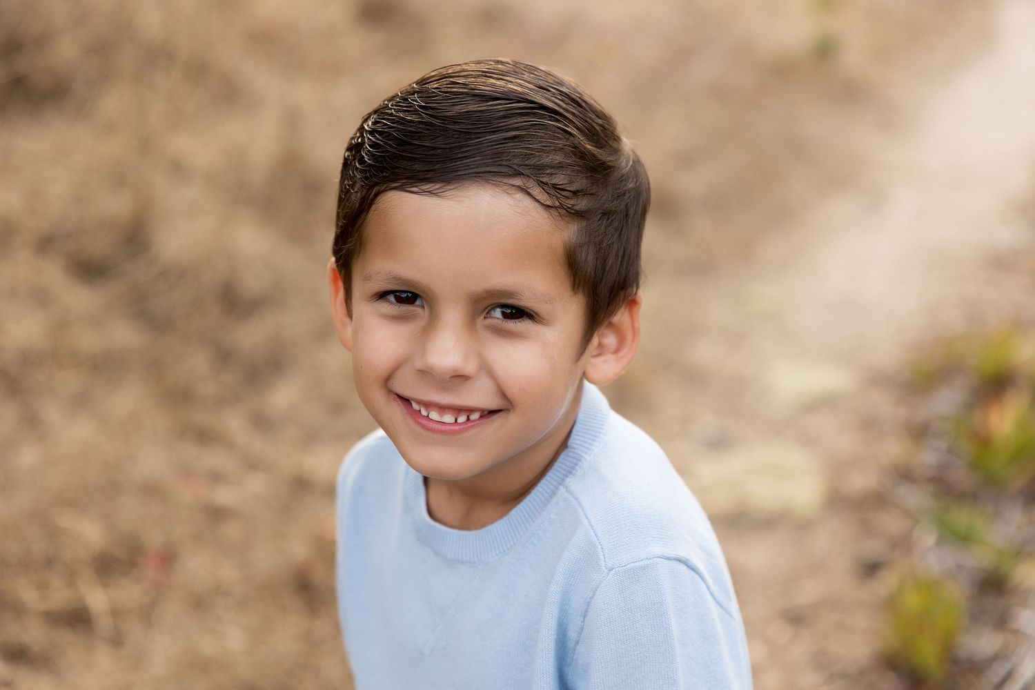 Young child in light blue sweater photographed outdoors.