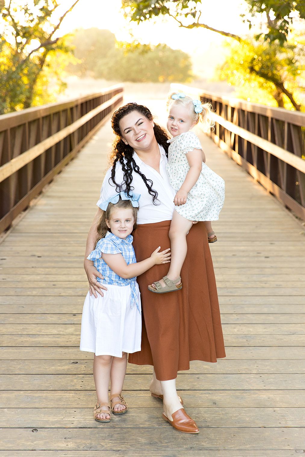 A series of candid family photos taken on a wooden bridge with warm golden sunlight filtering through trees in the background.