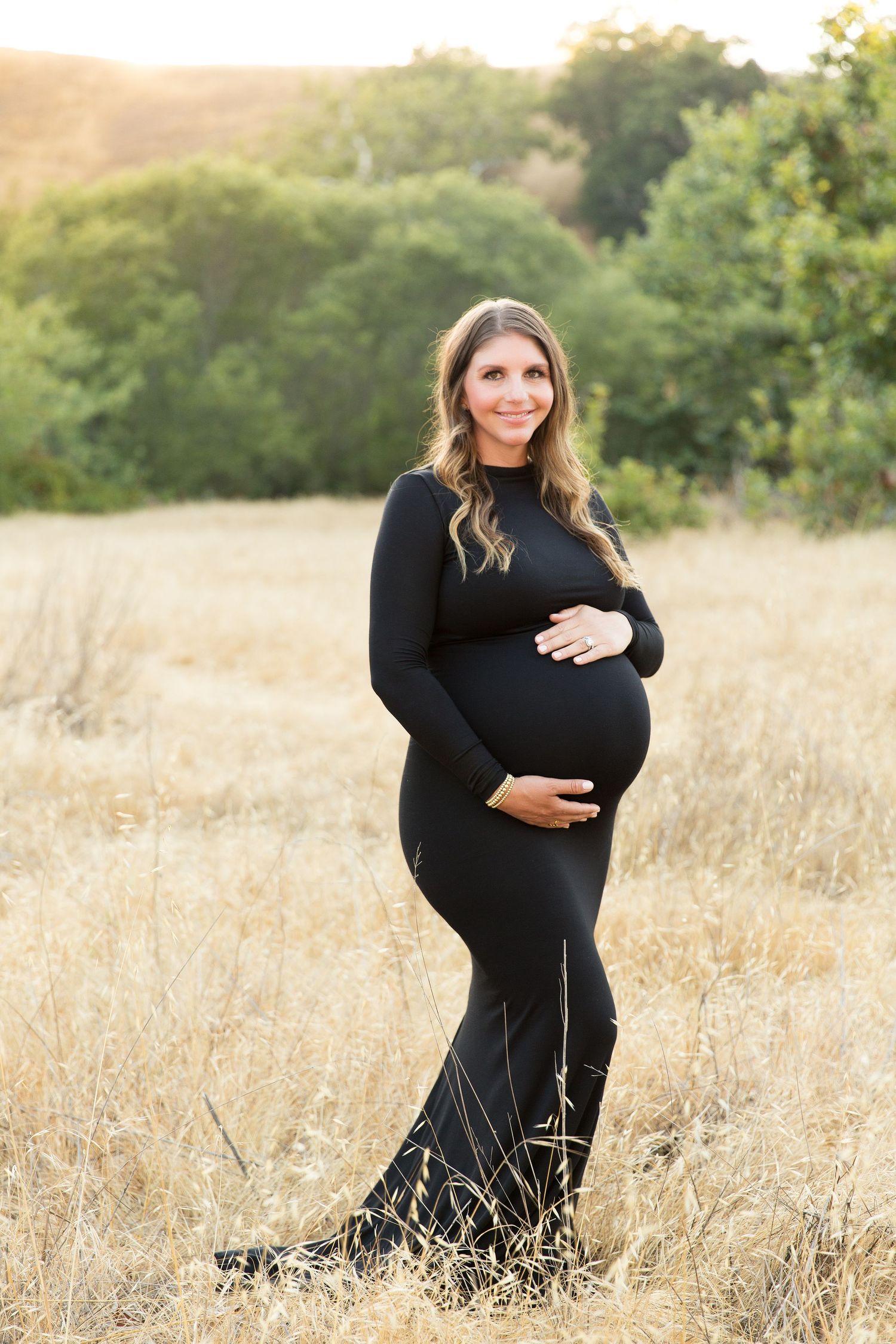 Golden hour maternity photos in a rustic field with tall grass.