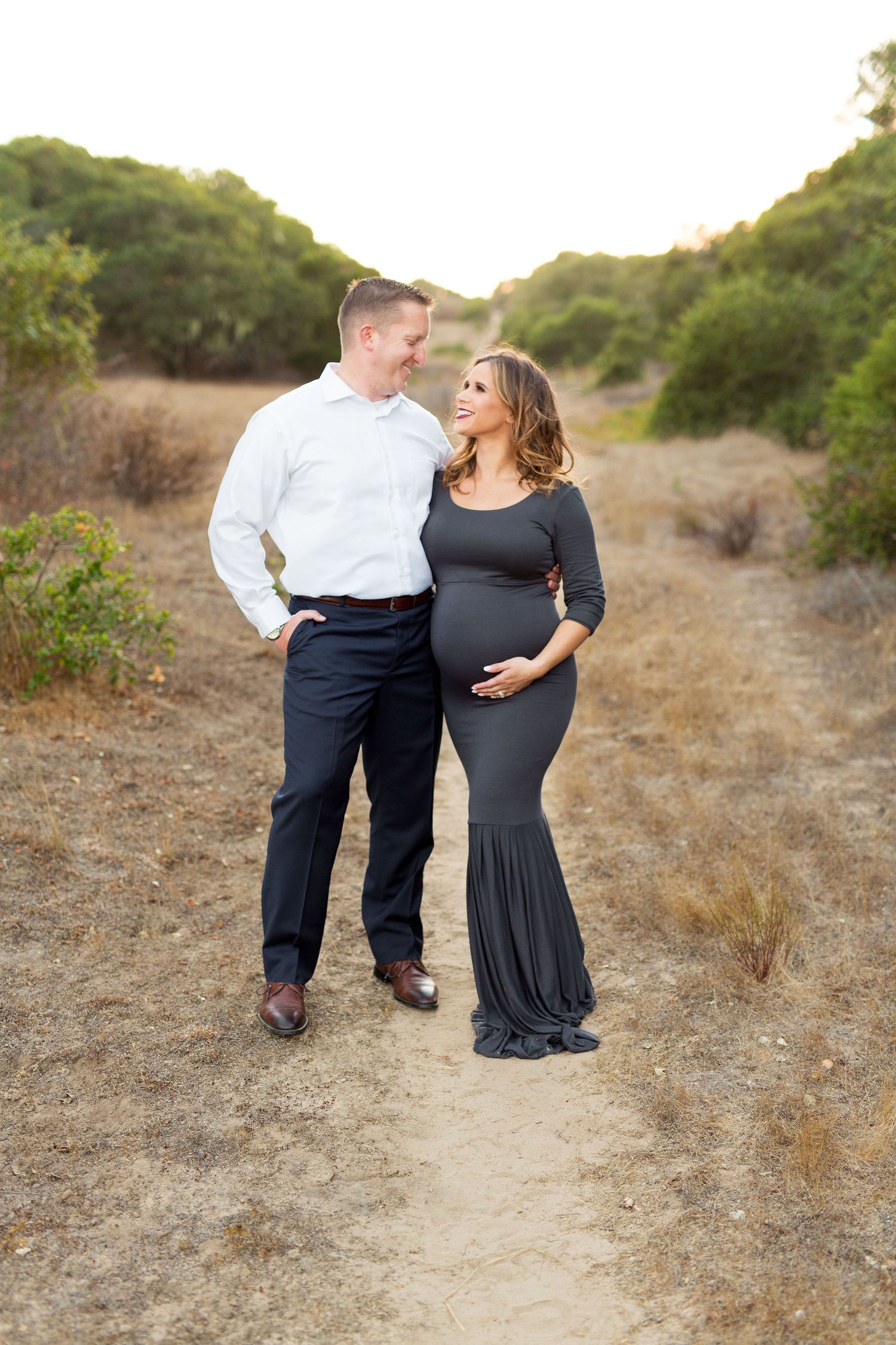 Two people share an intimate moment on a nature trail during a warm sunset.
