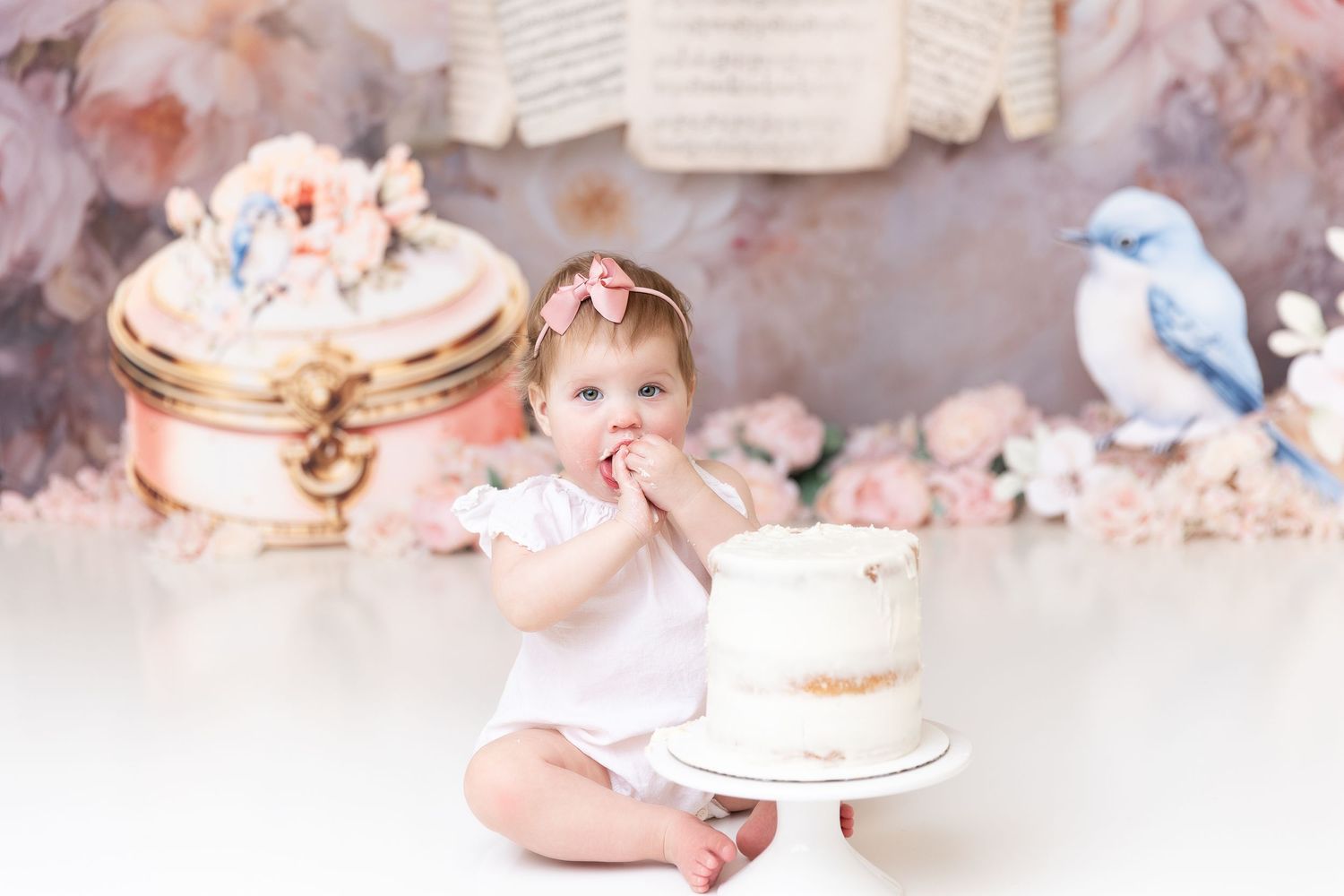 Vintage-styled cake smash setup with books and floral decorations.