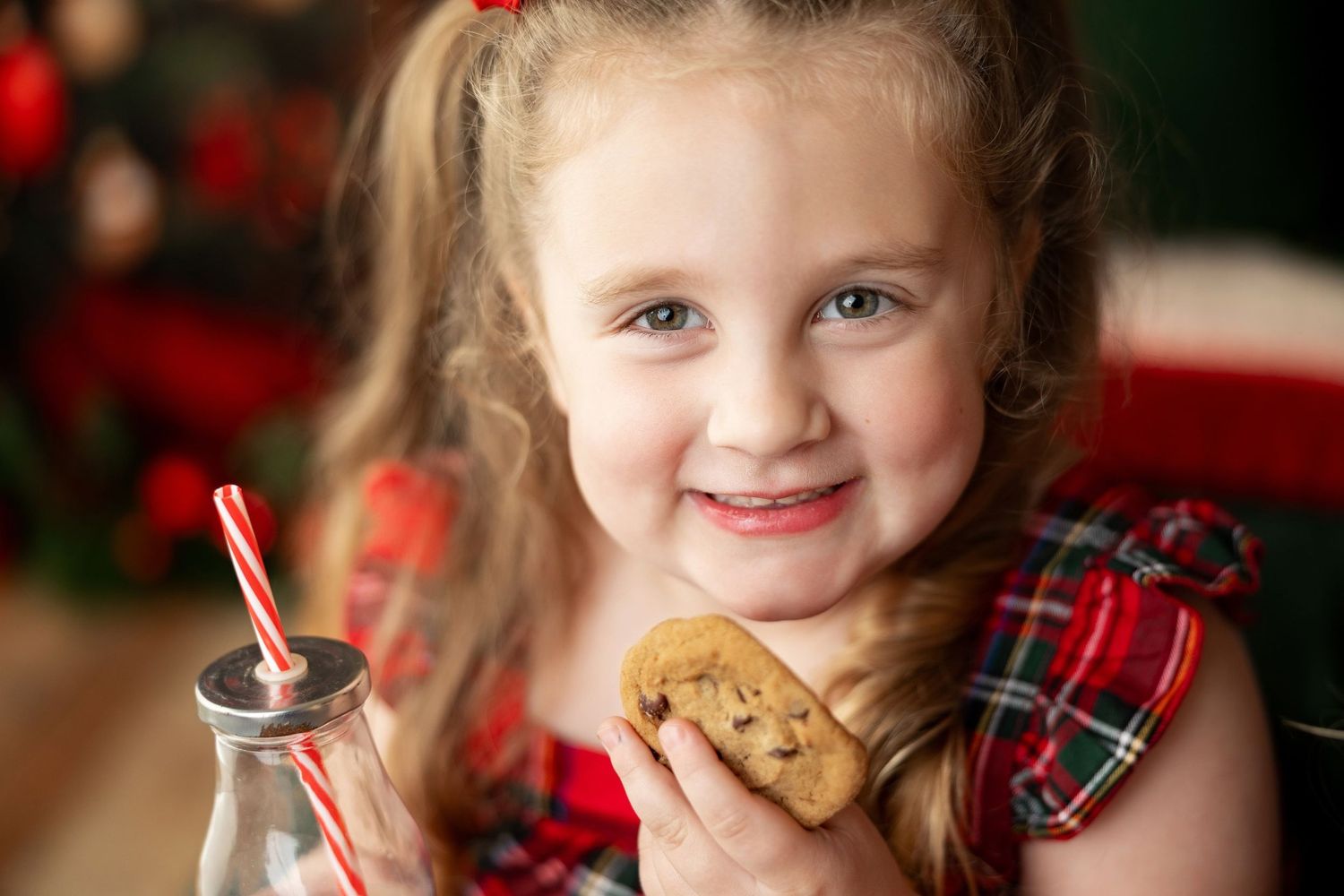 Girl with a chocolate chip cookie and milk bottle at a Christmas Milk & Cookies mini session in Pacific Grove