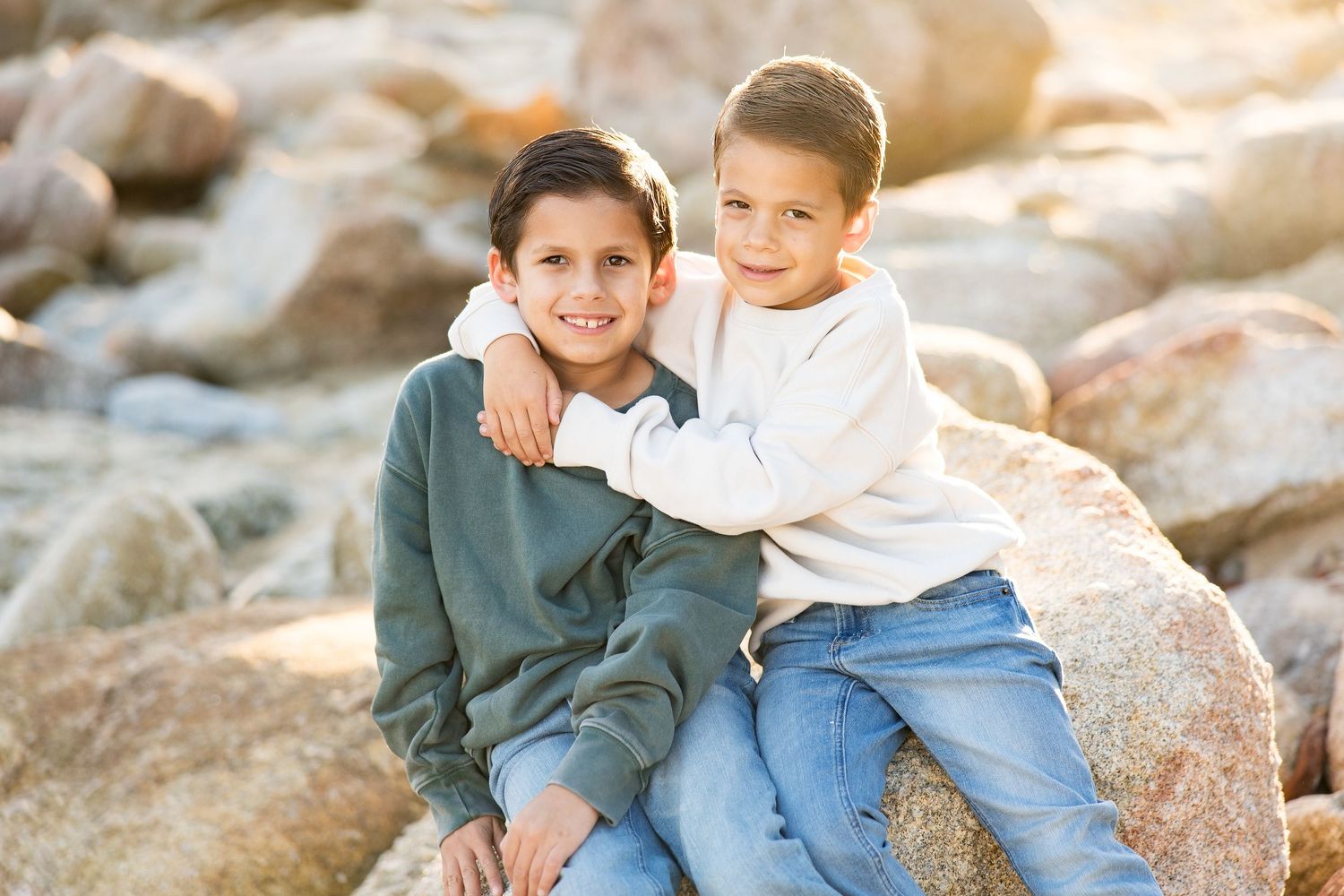 Casual family moments captured on rocky coastal terrain during golden hour.