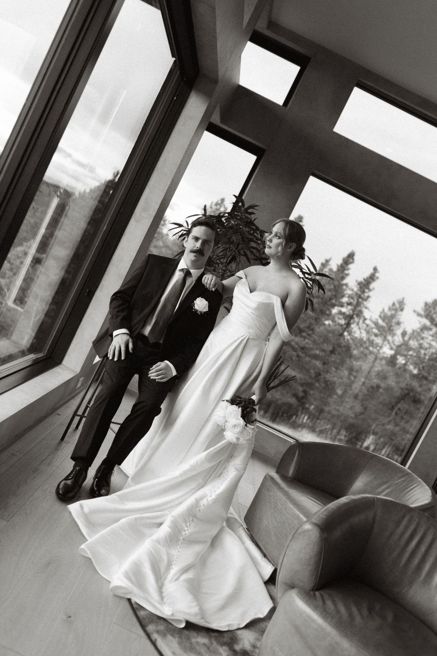 bride and groom posing by window