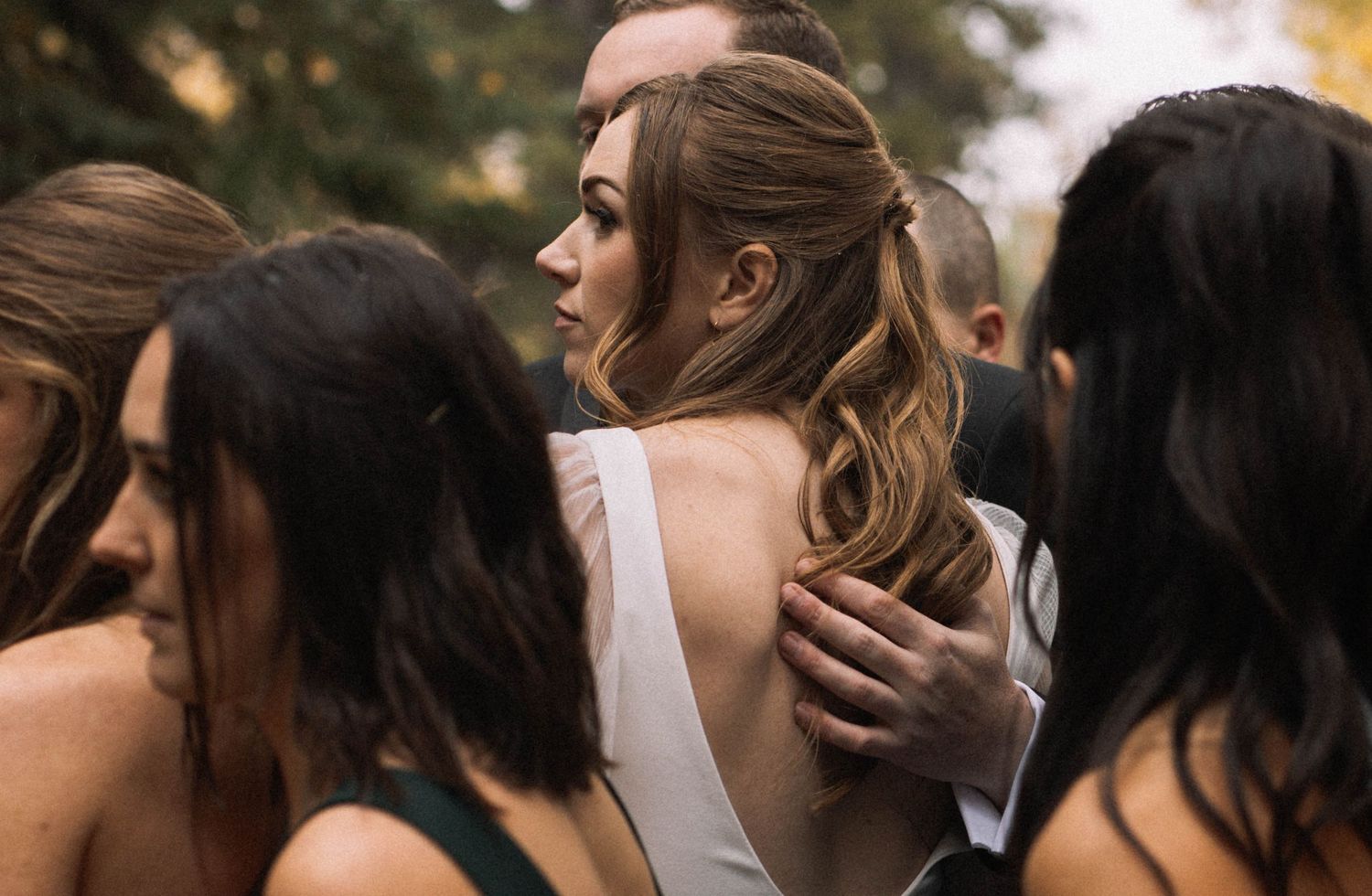 Bridesmaids in elegant dresses gathered together at an outdoor wedding.