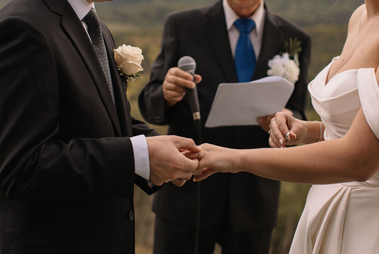 groom putting ring on his brides finger