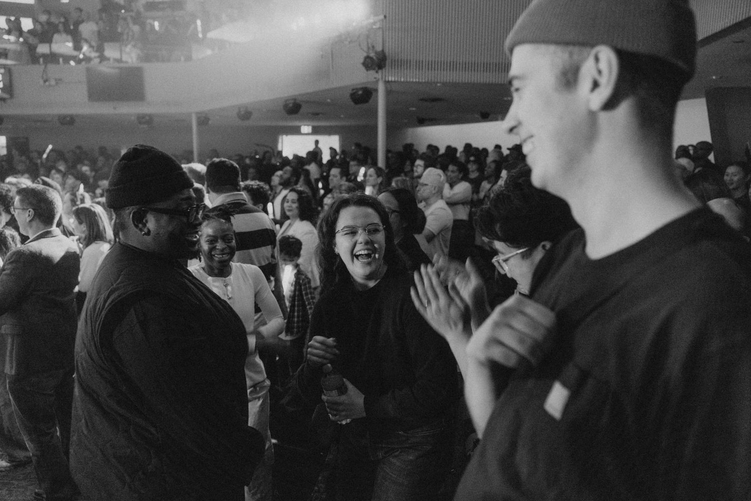 Crowd of people gathered in a dimly lit indoor space.