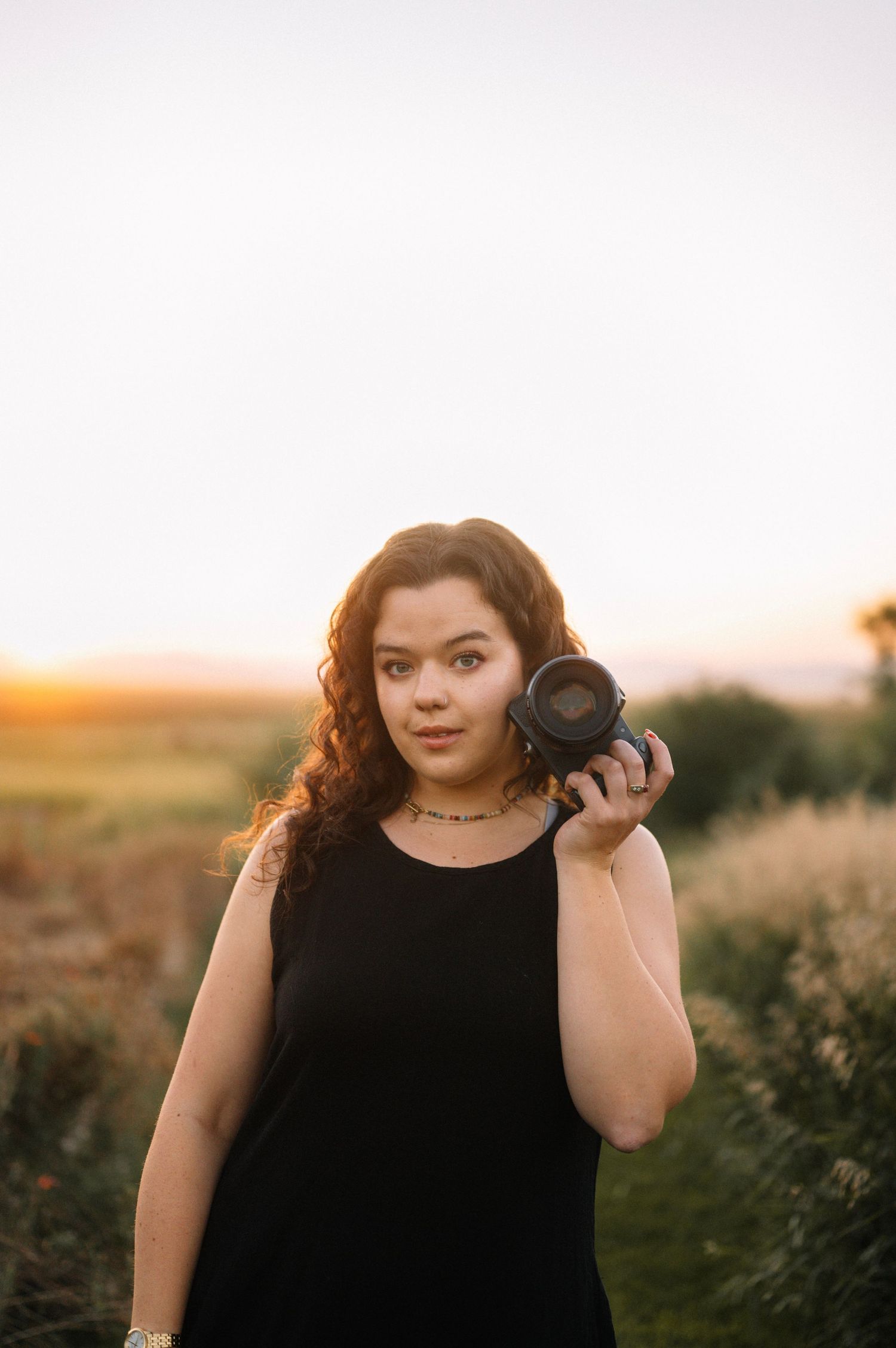 Photographer with camera against golden sunset backdrop.