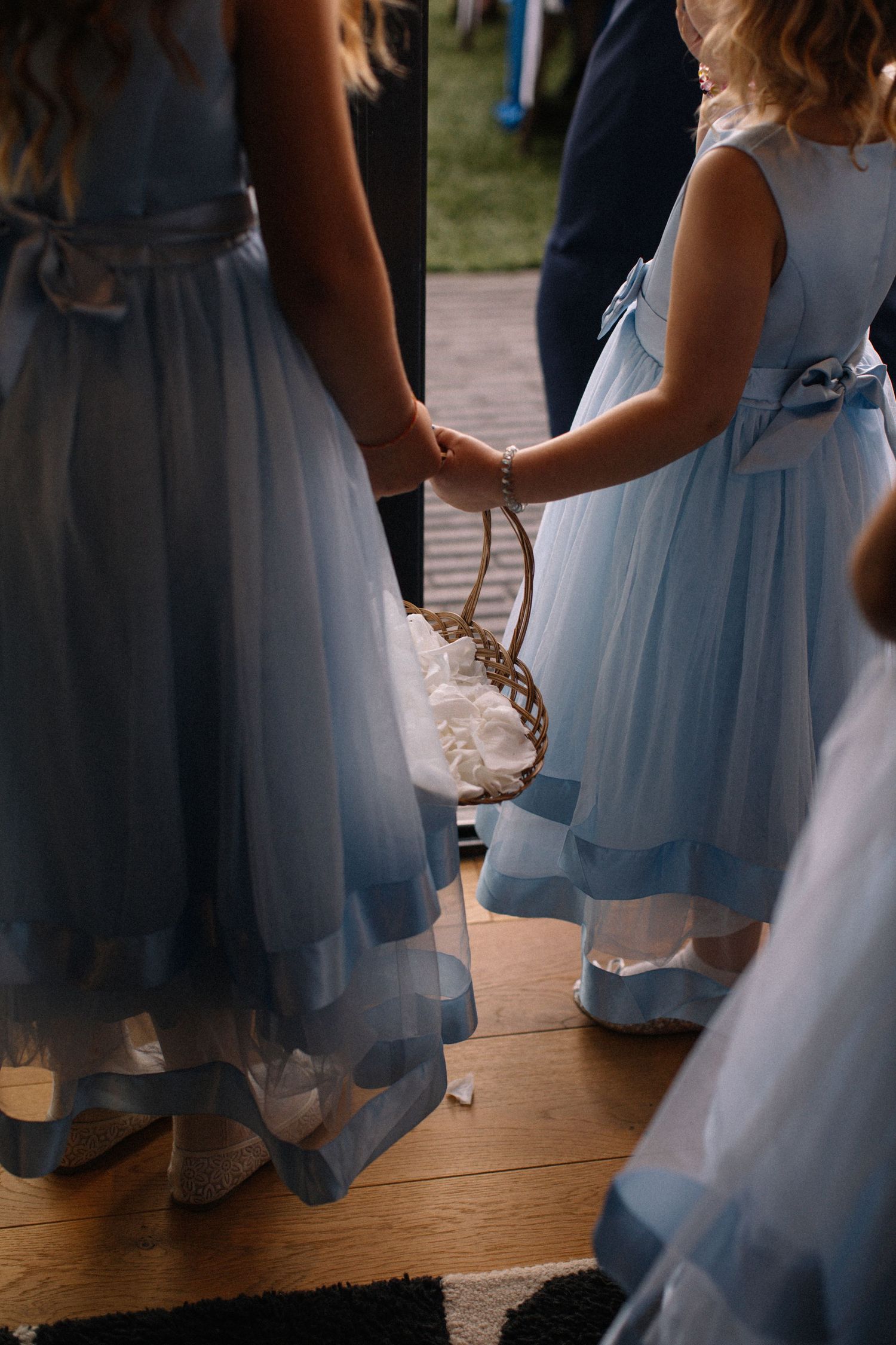 Wedding party members in light blue dresses gather on a wooden dance floor.