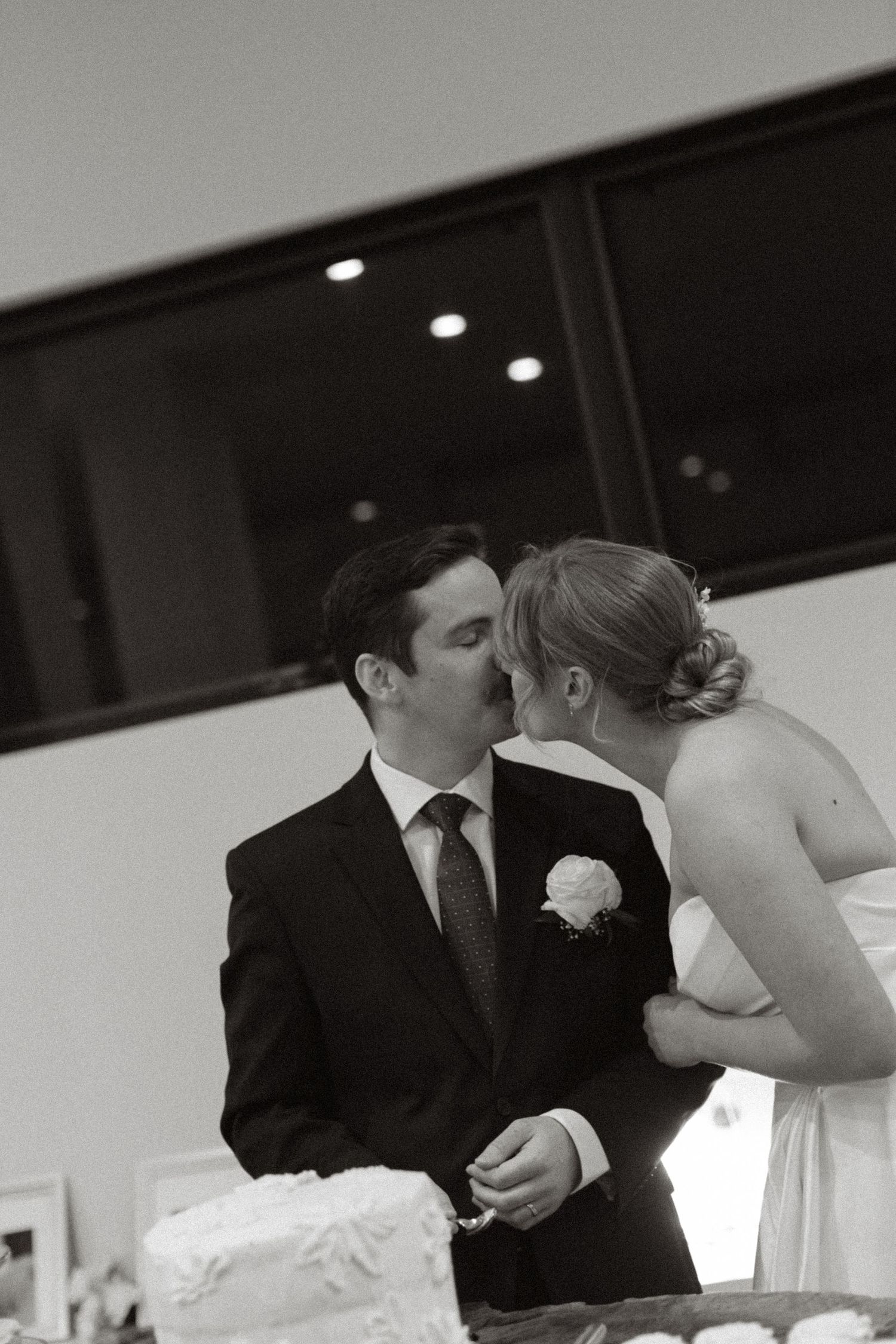 Bride and groom kissing cutting cake