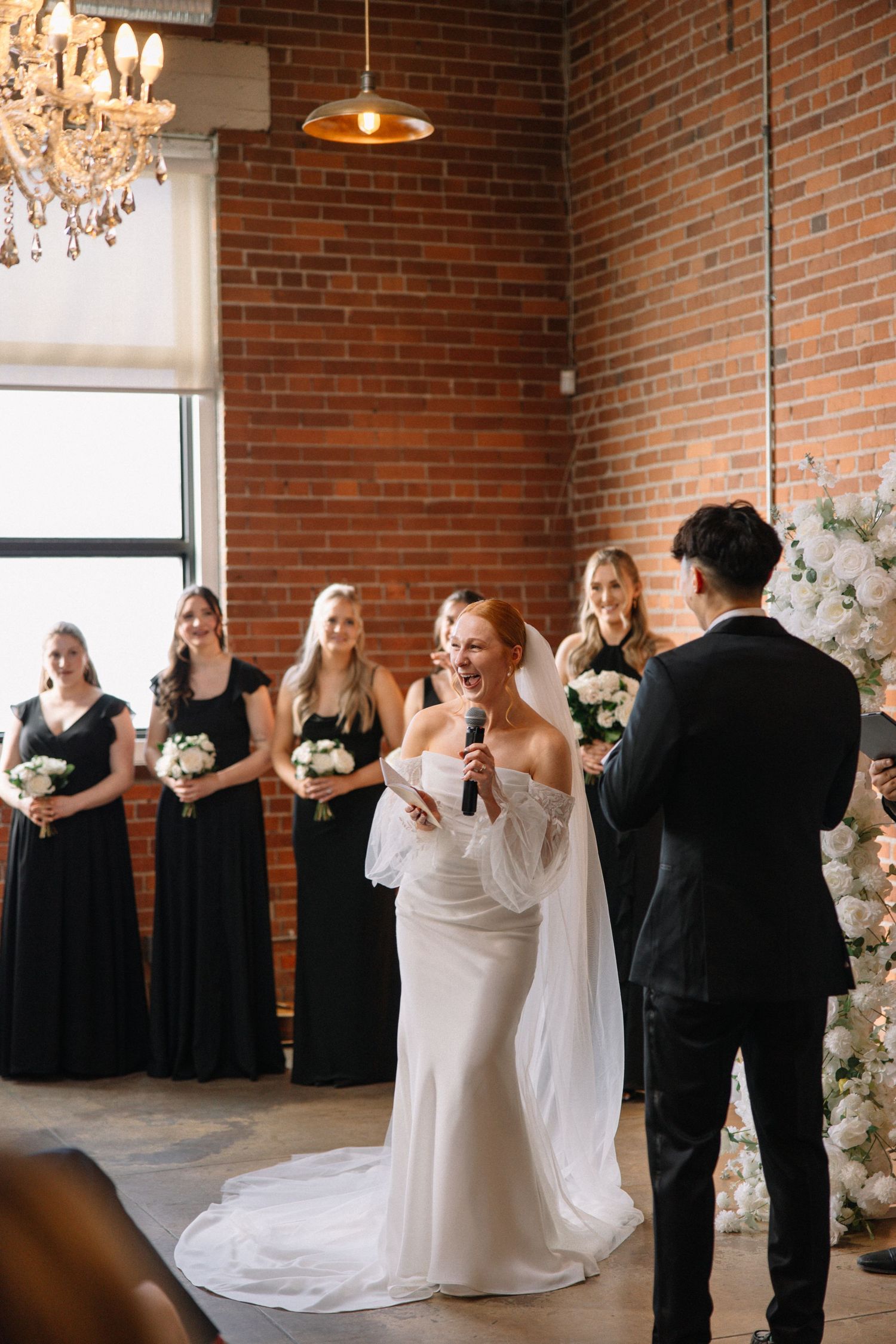 Wedding ceremony in industrial venue with exposed brick walls and crystal chandelier.