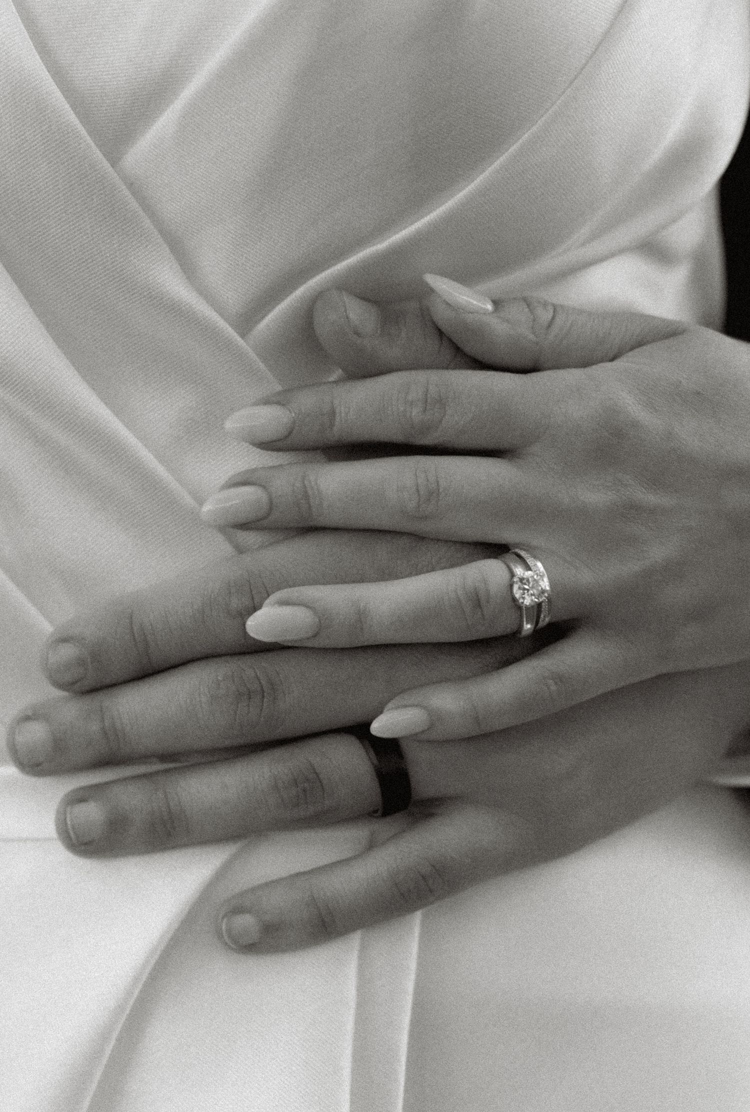 Black and white close-up sequence of hands with wedding rings resting on white fabric.
