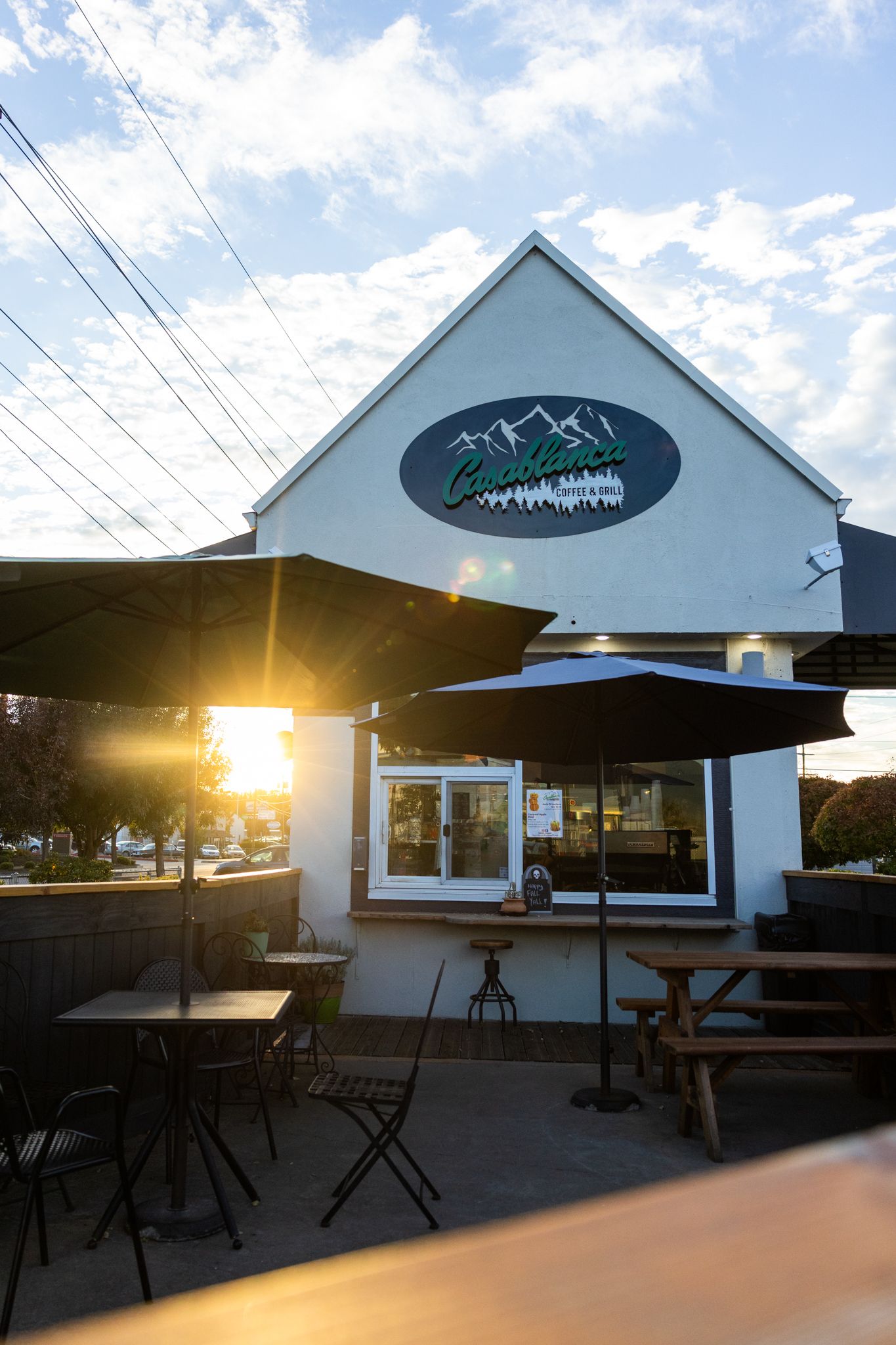 A series of sunset views of a white building exterior with outdoor seating and tables under an awning.
